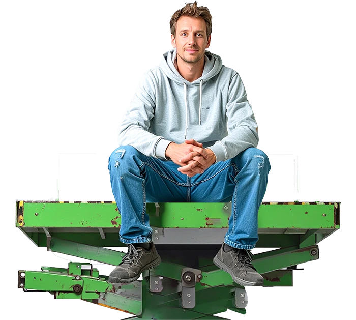 Mann in Hoodie und Jeans sitzt auf grüner Hebebühne und blickt entspannt in die Kamera.