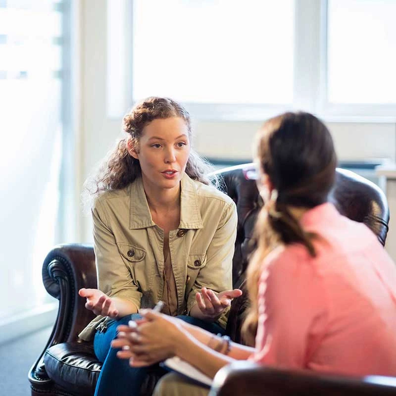 Zwei Frauen sitzen einander gegenüber und führen ein intensives Beratungsgespräch.