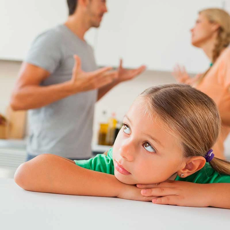 Mädchen schaut nachdenklich, im Hintergrund streiten sich zwei Erwachsene.